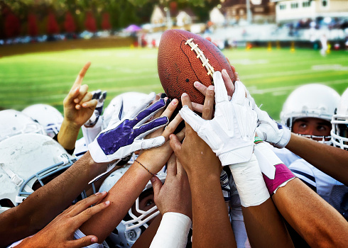 Football players holding up football.